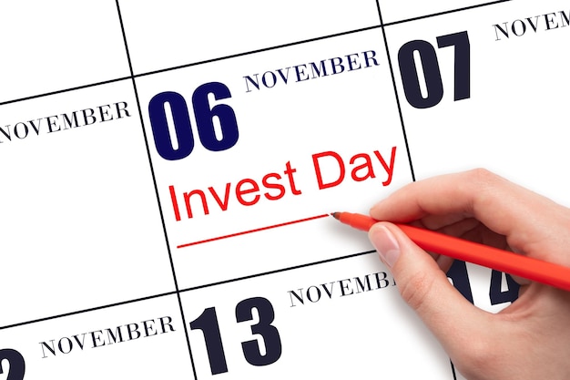 Hand drawing red line and writing the text Invest Day on calendar date November 6 Business and financial concept