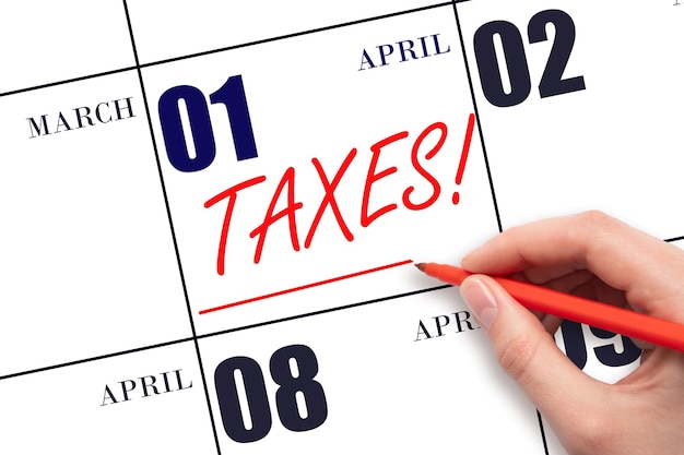 Hand drawing red line and writing the text Taxes on calendar date April 1 Remind date of tax payment