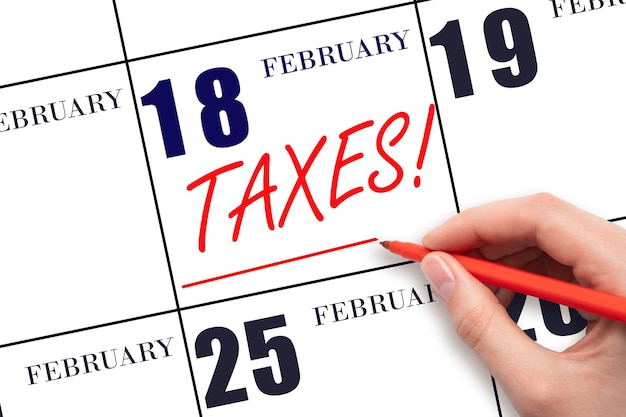 Hand drawing red line and writing the text Taxes on calendar date February 18 Remind date of tax payment