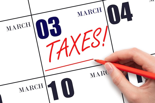 Hand drawing red line and writing the text Taxes on calendar date March 3 Remind date of tax payment