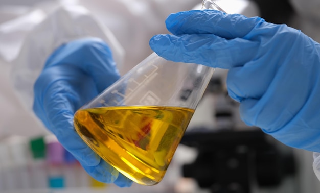 Hand drawn scientist holding laboratory glassware with golden oil liquid in chemistry lab