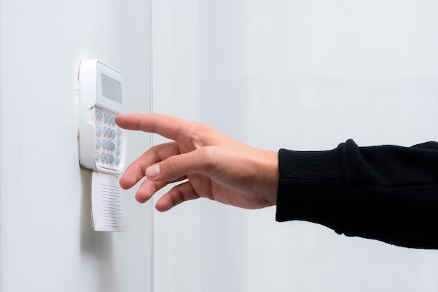 Hand entering alarm system password of an apartment, home or business office.