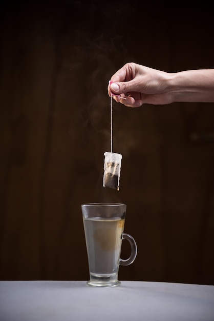 Hand entering a tea bag to prepare a hot breakfast room for copy