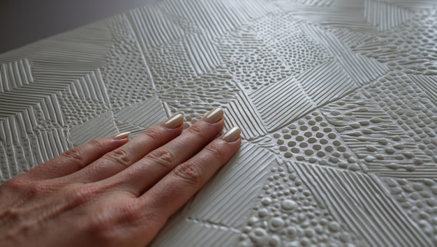 Photo a hand exploring textured wall art showcasing modern geometric patterns