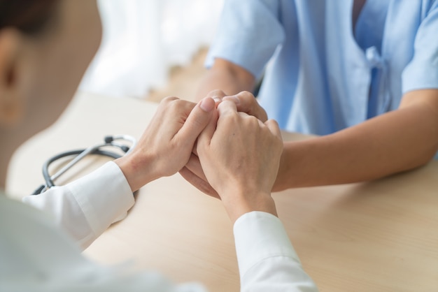 Hand of female doctor holding on her senior patient