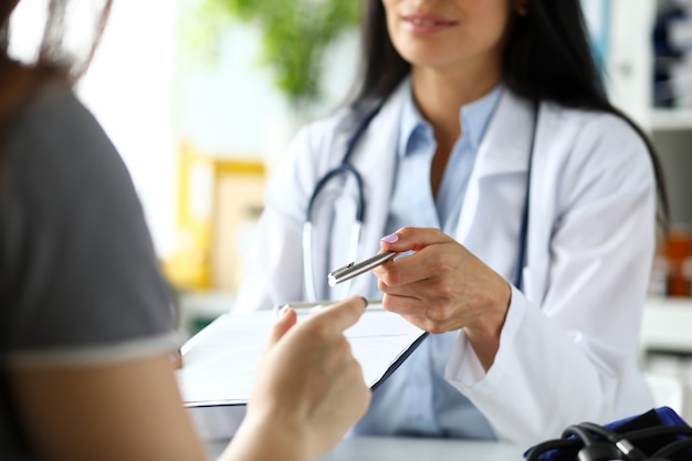 Hand of female GP passing to patient silver pen