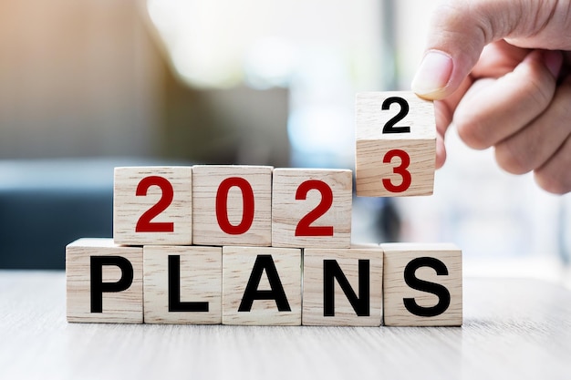 Hand flipping block 2022 to 2023 PLAN text on table Resolution strategy goal motivation reboot business and New Year holiday concepts