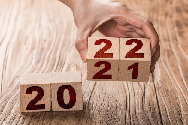 Photo hand flips a block changing 2021 to 2022 new year beginning holidays and christmas