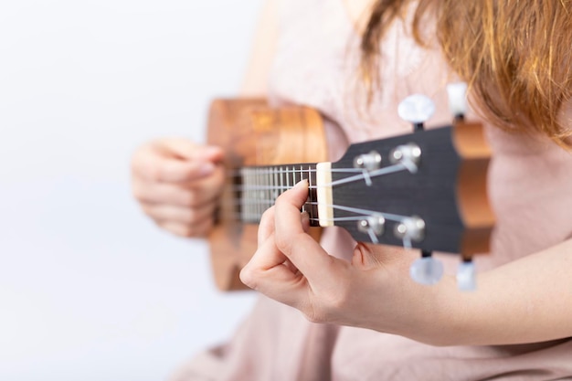 Hand of girl playing ukulele, small stringed instrument