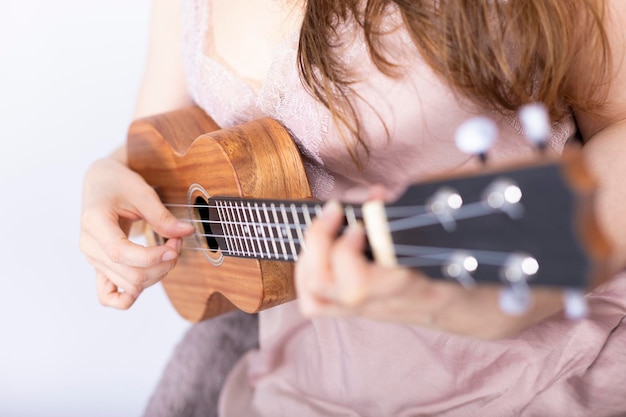 Hand of girl playing ukulele, small stringed instrument