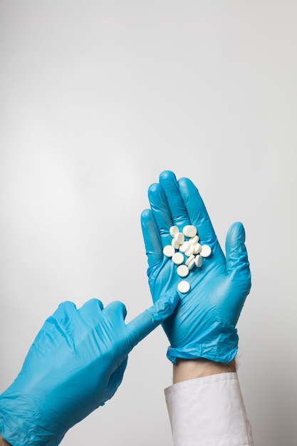 A hand in a glove holds a handful of pills