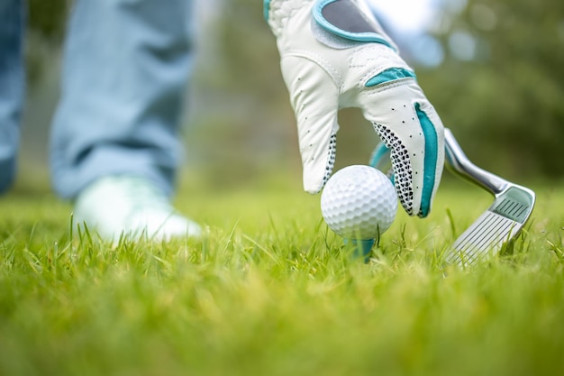 Hand in glove placing golf ball on tee