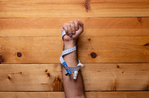 Hand grabbing soft measuring tape on light wooden background Labor Day