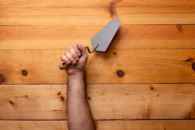 Hand grabbing trowel on light wooden background Labor Day