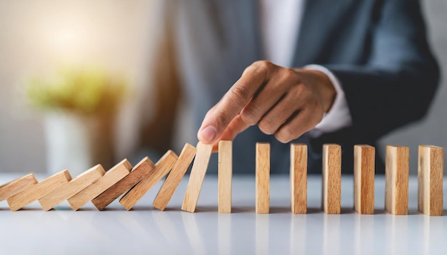 Hand halting wooden dominoes Symbolic of preventing business crises risk management and protectiv