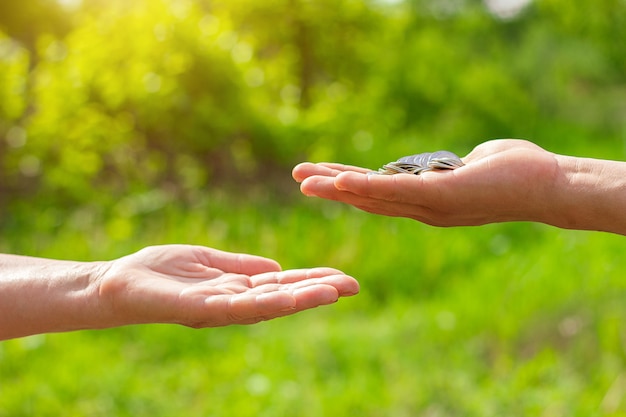 Hand in hand gives coins on green background, Finance concept and loans.