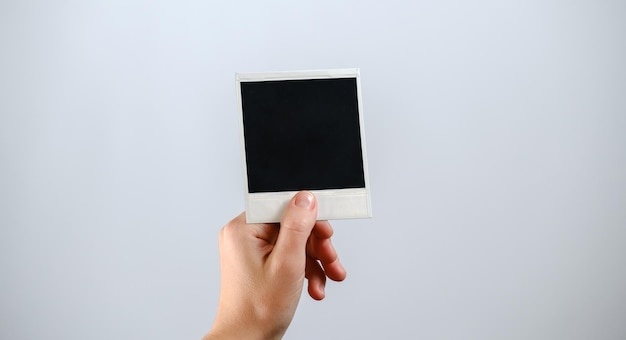 Hand hold blank photo paper card on white background holding a blank card