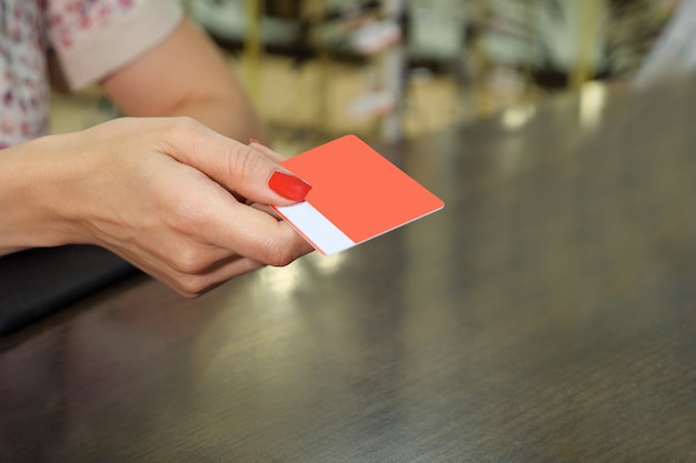 Hand hold blank red loyalty card mockup with rounded corners. Plain vip mock up template holding arm, close up.