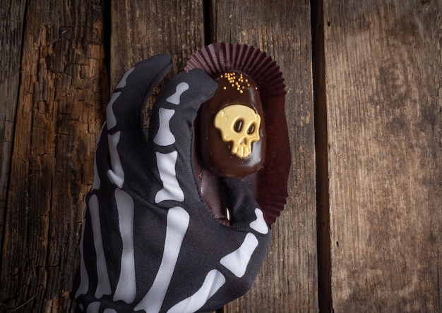 Hand hold chocolate cake with gold skull