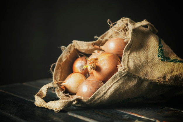 Hand hold fresh onion cloth bag isolated on wooden surface b