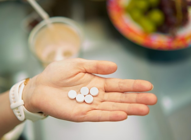 Hand hold medicine tablets in palm show with blur food and drinks background in vitamin health concept