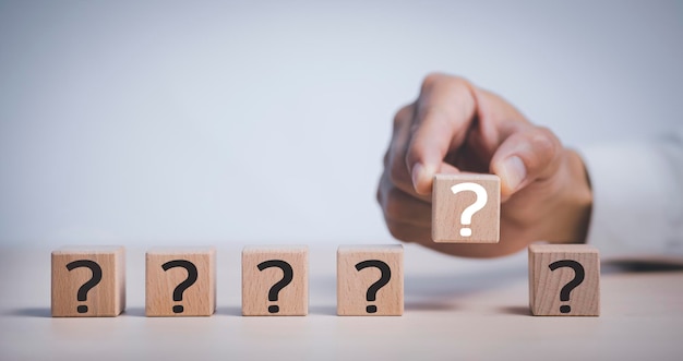 Hand hold Wooden cube block in question mark mean what on cement table background column of wooden blocks with question sign mark copy spaceFAQ frequently asked questions Answer Information