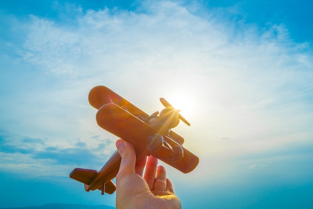 The hand hold the wooden plane on the background of the sunrise