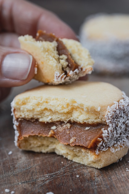 Hand holding an alfajores cookies on old wood