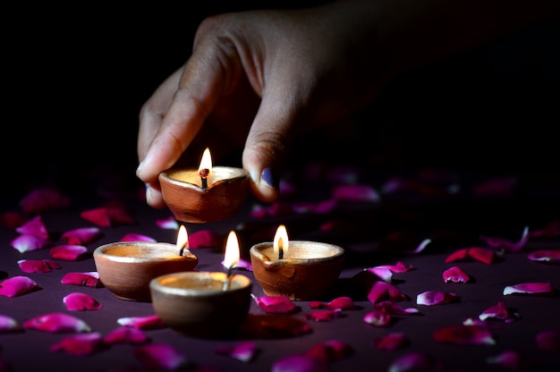 Hand holding and arranging lantern (Diya) during Diwali Festival of Lights