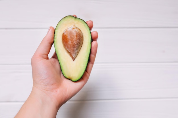 Hand holding avocado half on white background healthy food