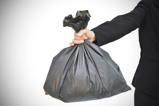 Hand holding a black garbage bag on grey background with clipping path