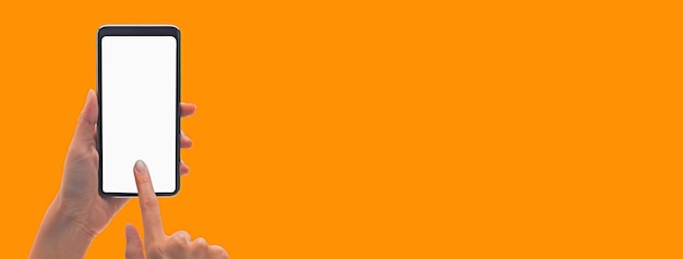 Photo hand holding the black smartphone and touching blank screen on colorful orange banner background clipping path