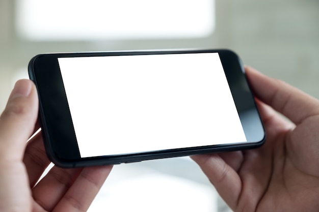 a hand holding blackmobile phone with blank white desktop screen 