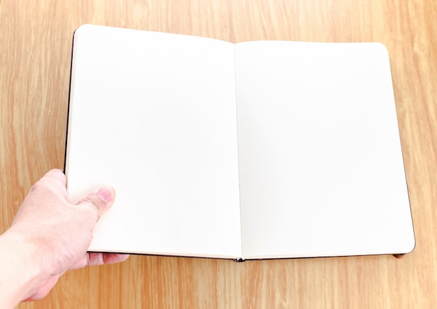 Hand holding blank open notebook lay it on wooden table,Template mock up for adding your text