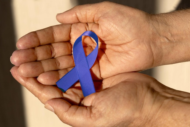 Hand holding a blue ribbon Blue november