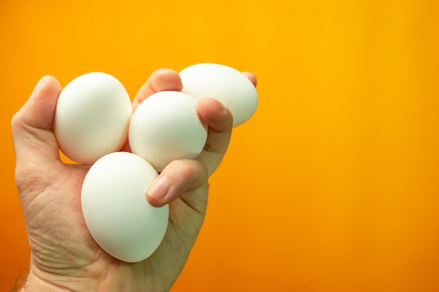 Hand holding boiled eggs on a orange background