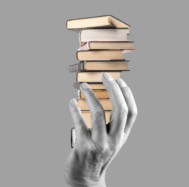 Hand holding books stack on grey background Knowledge intellectual development wisdom literature importance concept Black and white