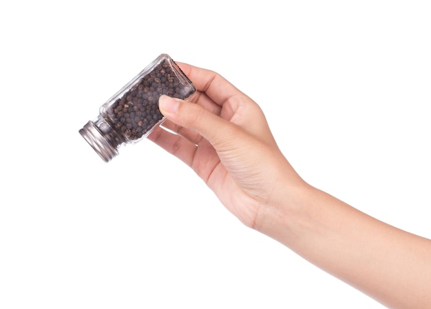 hand holding bottle of Black pepper and coriander seeds isolated on white background