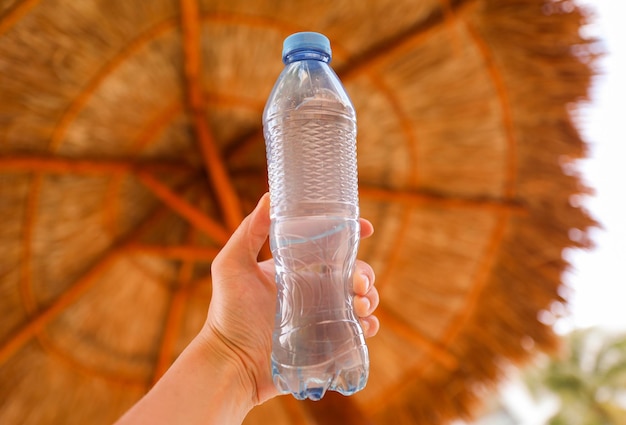 A hand holding a bottle of water that says " water " on it.