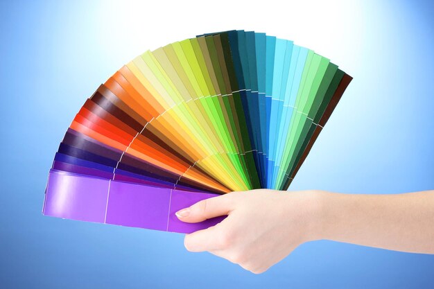 Hand holding bright palette of colors on blue background