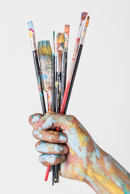 Hand holding brushes stained with paint