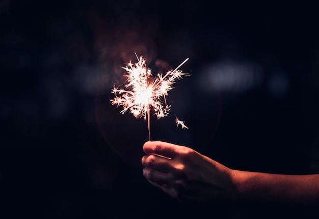 Hand holding burning Sparkler blast on a black background