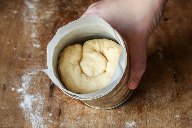 hand holding canned dough over rustic table