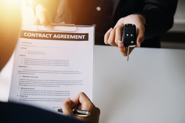 Hand holding car keys and car rental concept A closeup view of the agent giving the customer the car keys after signing the lease rental form and car name