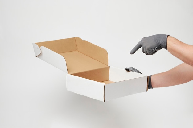 Hand holding cardboard box on over white background with copy space Delivery and shipping service concept Hand delivery pizza box closeup