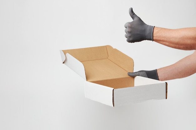 Hand holding cardboard box on over white background with copy space Delivery and shipping service concept Hand delivery pizza box closeup