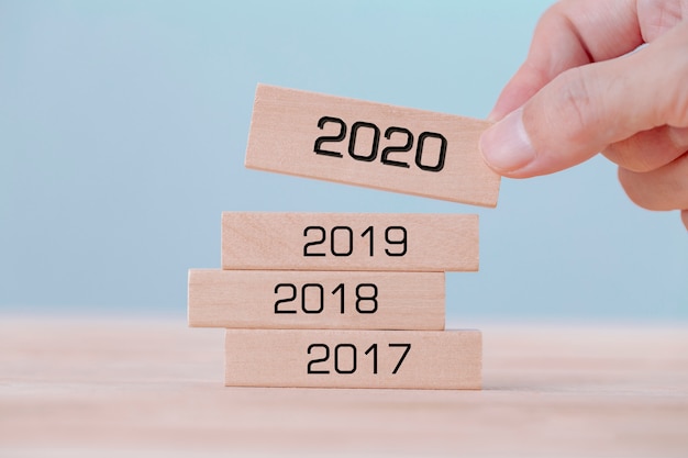 Hand holding chooses wooden block cubes with word 2020