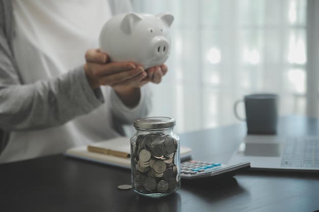 Hand holding coin with pig piggy bank Saving and financial accounts concept