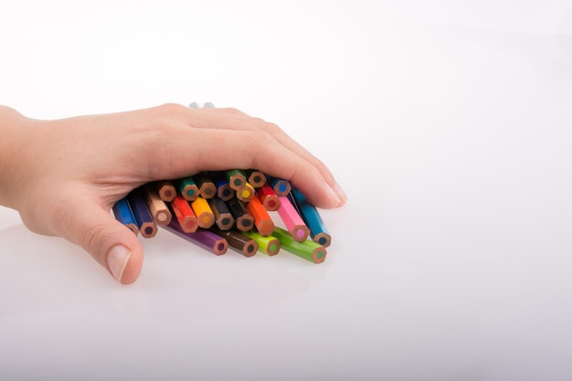 Hand holding color pencils on a white background