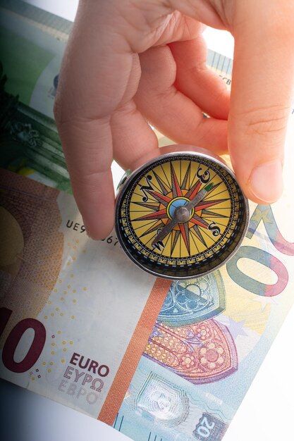 Hand holding compass on Euro banknotes as business finance concept